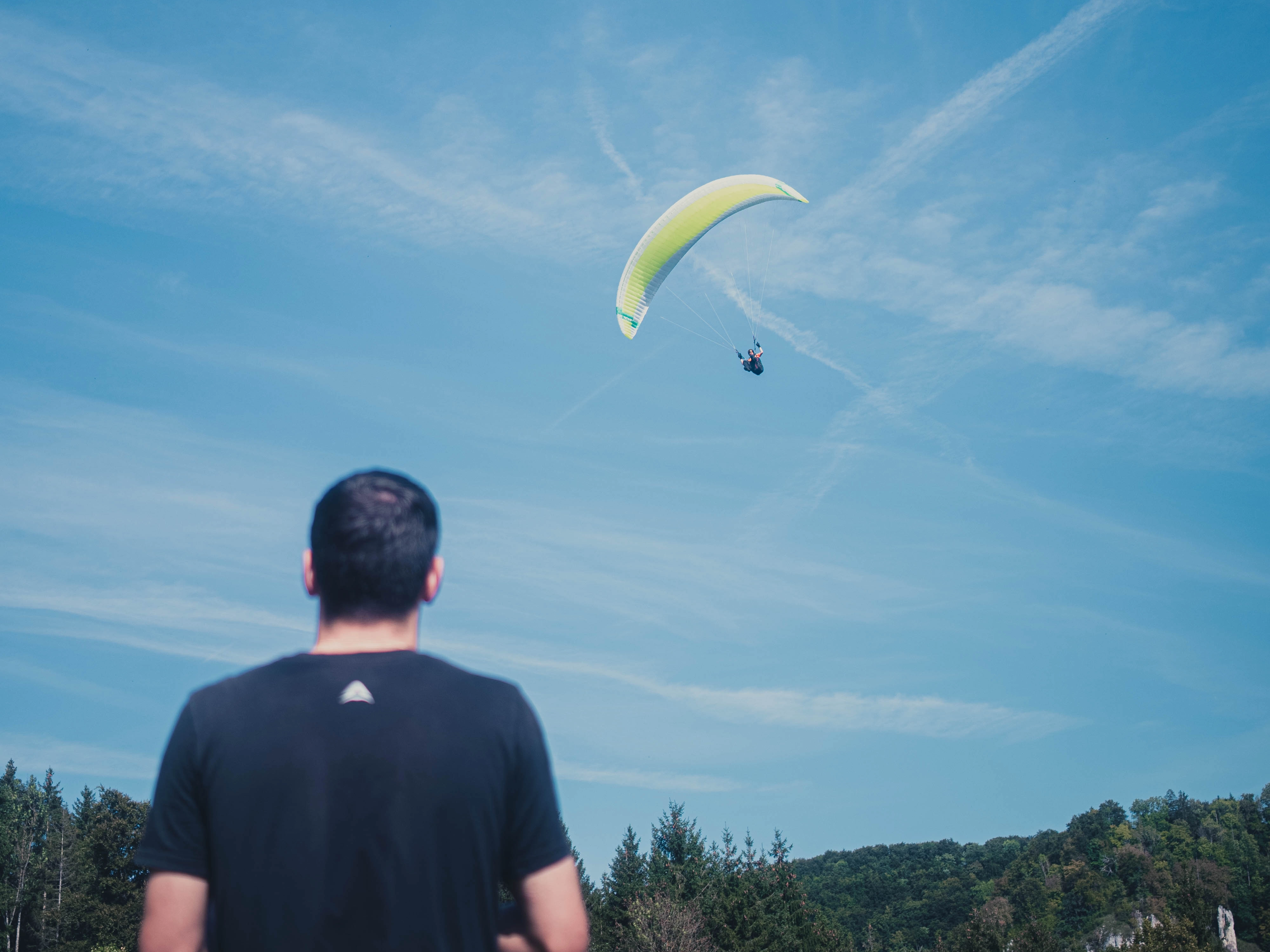 Orangener Gleitschirm fliegt vor blauem Himmel